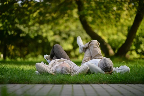 快乐的资深夫妇摆在公园里躺在草地上 — 图库照片
