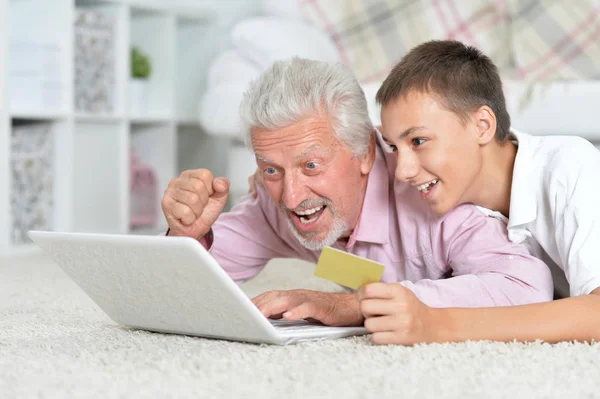 Avô Neto Deitado Chão Usando Laptop Neto Segurando Cartão Crédito — Fotografia de Stock