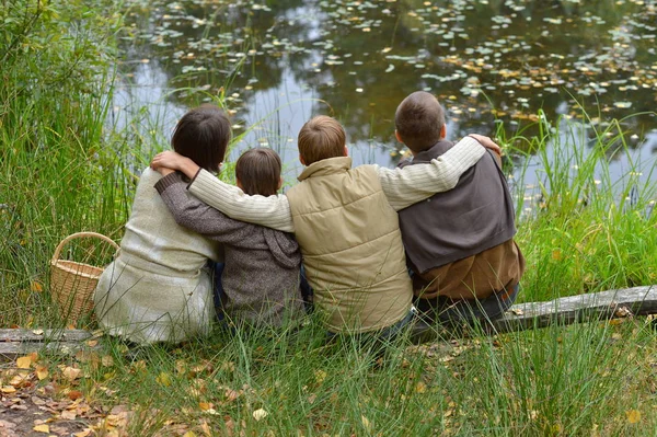 秋天森林里快乐的微笑家庭坐在湖边 — 图库照片