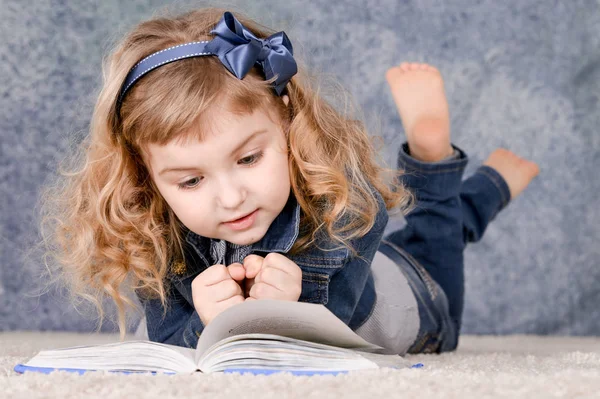 床に横たわっている間本を読んでかわいい女の子 — ストック写真
