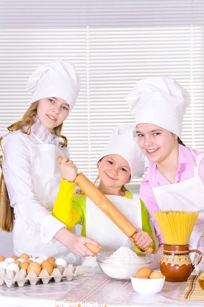 可爱的小女孩在厨师的帽子和围裙准备在家里的厨房面团 — 图库照片