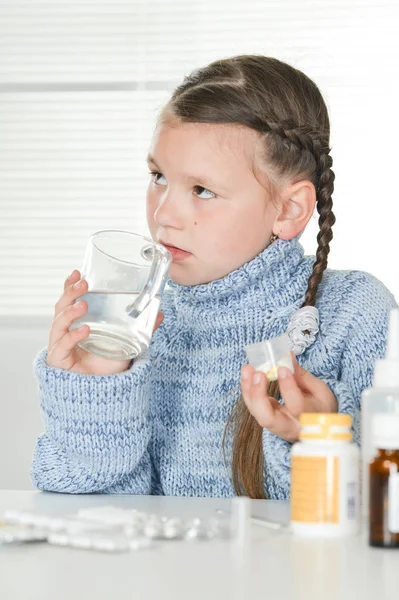 年轻生病的女孩坐在餐桌上吃药 — 图库照片