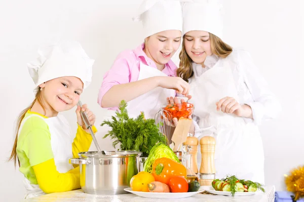 可爱的小女孩在厨师的帽子和围裙准备晚饭在家里的厨房 — 图库照片