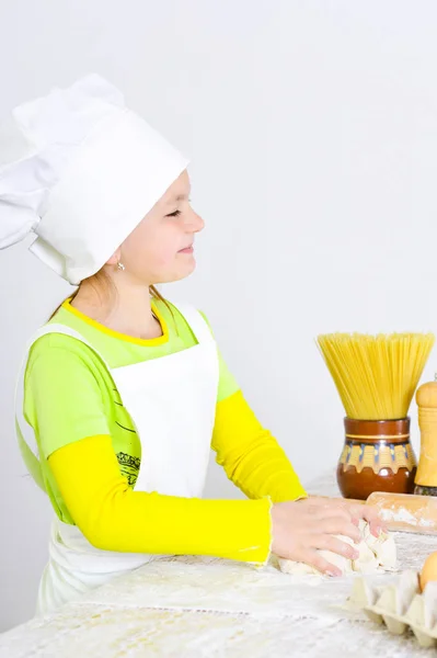 自宅の台所でケーキを焼くシェフの帽子でかわいい女の子 — ストック写真
