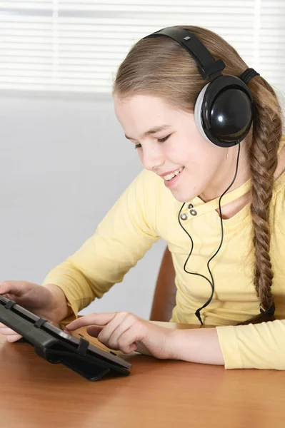 十几岁的女孩坐在餐桌旁和使用平板电脑 — 图库照片