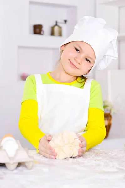 可爱的小女孩在厨师的帽子烘烤蛋糕在厨房在家 — 图库照片