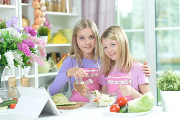 Две Девушки Фартуках Готовят Свежий Салат Кухонном Столе Планшетом — стоковое фото