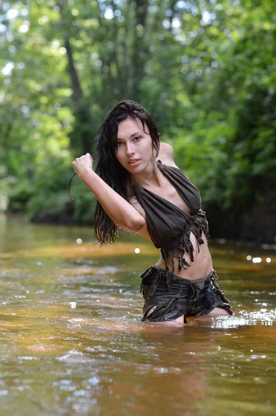 穿着黑色衣服的漂亮年轻女子在河里摆姿势 — 图库照片