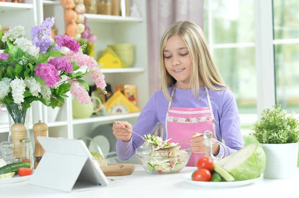 Roztomilá Dívka Připravuje Čerstvý Salát Kuchyňském Stole Tabletu Doma — Stock fotografie