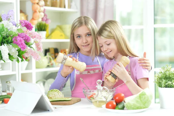 Dwie Dziewczyny Fartuchy Przygotowanie Sałatki Stole Kuchni Tabletem — Zdjęcie stockowe