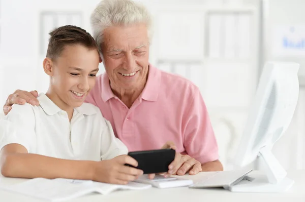 Adolescente Menino Avô Usando Smartphone Enquanto Sentado Mesa Computador — Fotografia de Stock