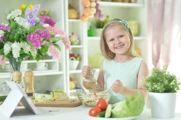 Симпатична Маленька Дівчинка Готує Салат Кухонному Столі Планшетом Вдома — стокове фото