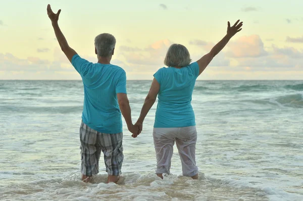 幸せな高齢者のカップルを手で熱帯のビーチで休んで — ストック写真