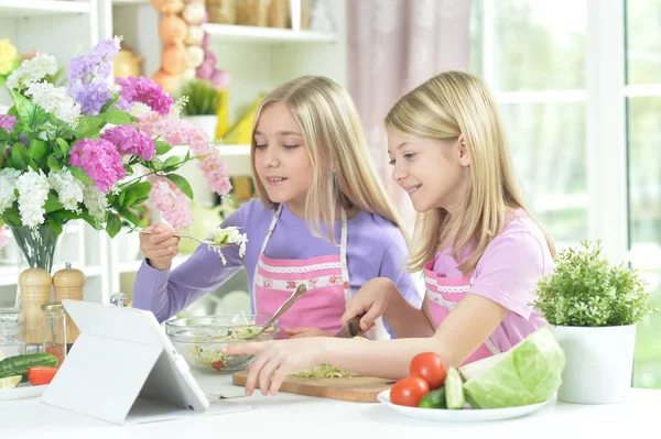 Zwei Mädchen Schürzen Bereiten Frischen Salat Auf Küchentisch Mit Tablette — Stockfoto