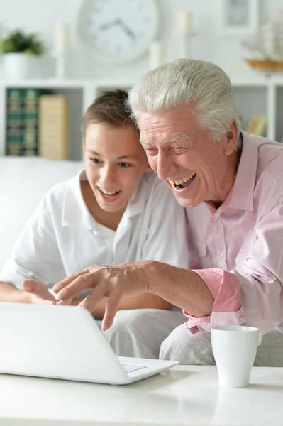男孩和祖父在家里带着笔记本电脑的肖像 — 图库照片