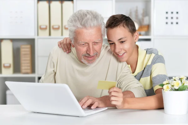 ネットショッピングでノートパソコンを手にした少年と祖父の肖像画 — ストック写真