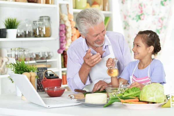 Senior Mit Enkelin Schaut Auf Laptop Während Küche Essen Zubereitet — Stockfoto