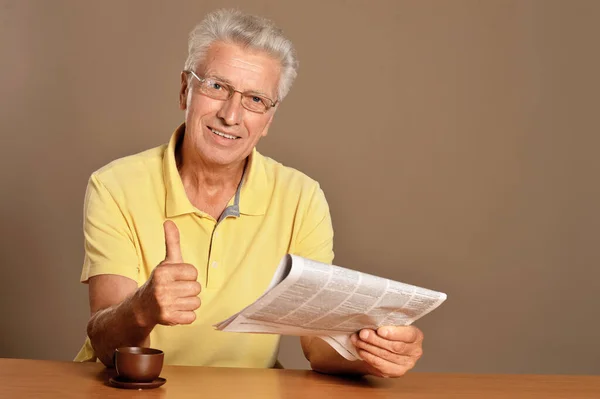 Senior Man Reading Newspaper Showing Thumb — Stock Photo, Image