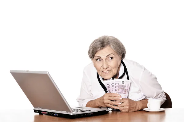 Médico Senior Sentado Mesa Con Portátil Sosteniendo Dinero —  Fotos de Stock