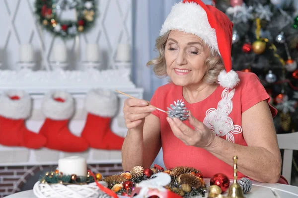 Porträt Einer Lächelnden Seniorin Mit Weihnachtsmann Hut Und Tannenzapfen Dekoration — Stockfoto