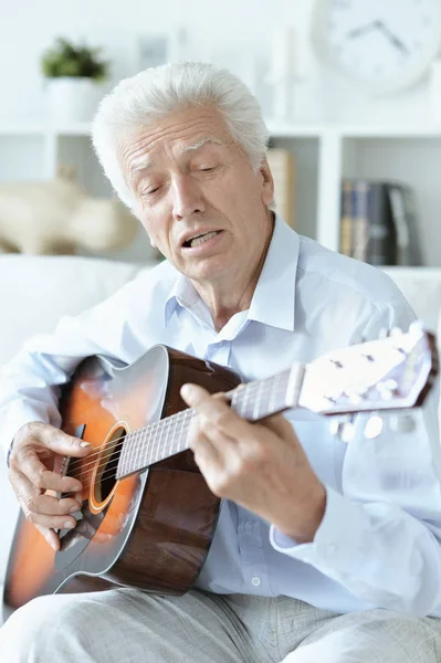 快乐老人与吉他坐在家里的沙发上 — 图库照片