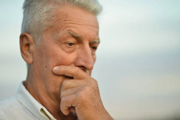 Portrét Smutného Staršího Muže Proti Modré Oblačné Obloze — Stock fotografie