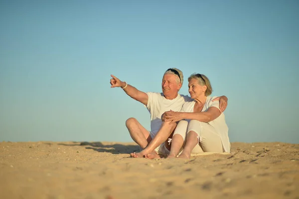 Happy Elderly Couple Sitting Tropical Beach Man Pointing — Stock Photo, Image