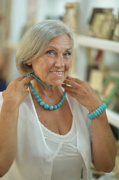 ネックレスを試着しているお土産店で美しい笑顔の先輩女性 — ストック写真