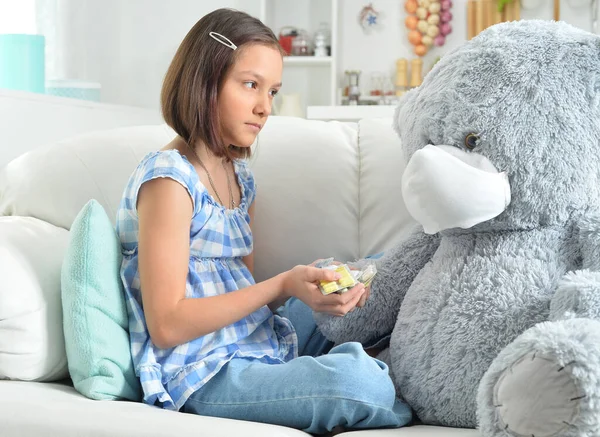 Menina Dando Pílulas Para Brinquedo Ursinho Pelúcia Máscara Facial Sofá — Fotografia de Stock