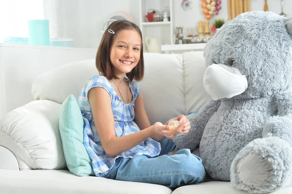女孩在沙发上给戴着面具的玩具泰迪熊吃药 — 图库照片