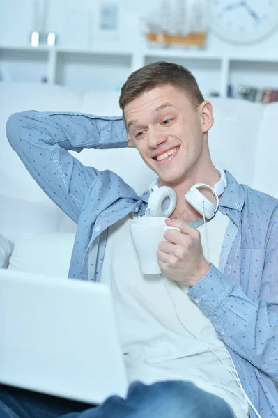 Joven Guapo Acostado Sofá Blanco Con Ordenador Portátil Beber Café —  Fotos de Stock