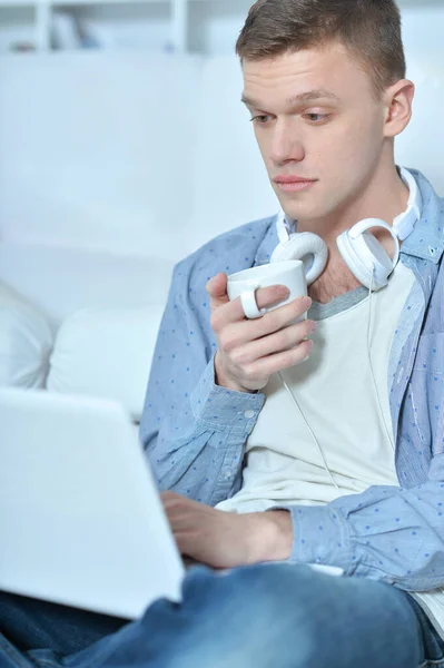 Красивый Молодой Человек Лежит Белом Диване Ноутбуком Пьет Кофе — стоковое фото