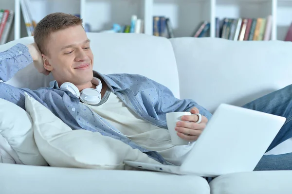 Jovem Bonito Deitado Sofá Branco Com Laptop — Fotografia de Stock