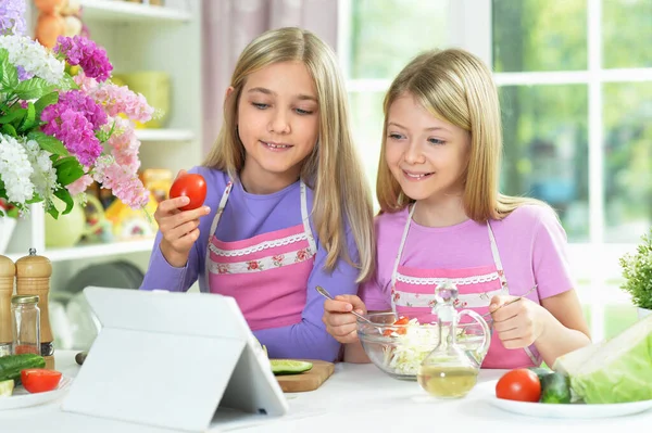 Twee Meisjes Roze Schorten Bereiden Salade Keukentafel Met Tablet — Stockfoto