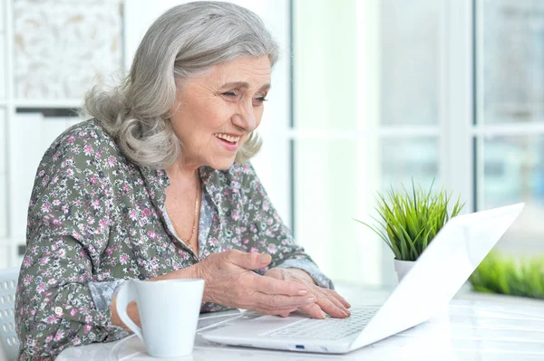 漂亮的老妇人在家里用笔记本电脑 — 图库照片