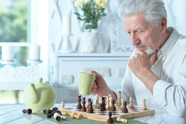 Portrait Senior Man Looking Chess Board While Drinking Tea Home — Stok Foto