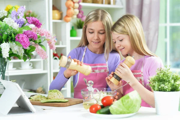 Two Girls Pink Aprons Preparing Salad Kitchen Table Tablet — Stock Photo, Image