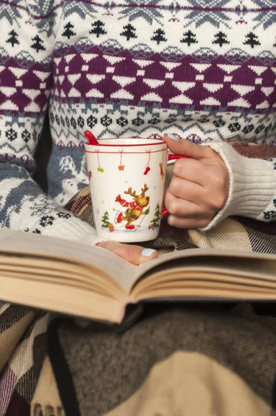 Female hands with cup of tea  and with a book - stock image