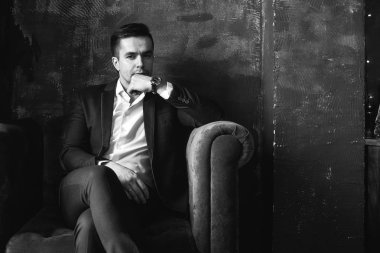 Kadife koltuğa oturan takım elbiseli dalgın işadamı portresi