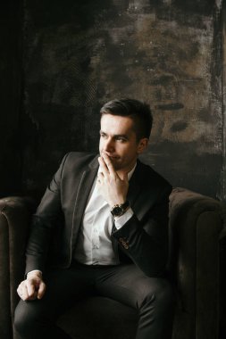 Kadife koltuğa oturan takım elbiseli dalgın işadamı portresi