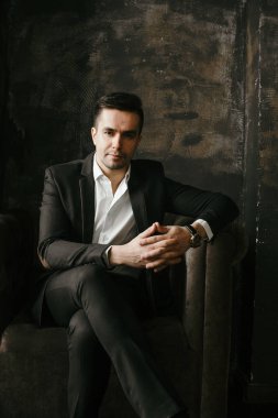 Kadife koltuğa oturan ve kameraya bakarak yakışıklı işadamı portresi 