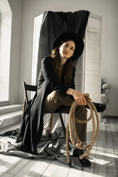 attractive brunette woman in fashion style clothes sitting on chair and posing in studio