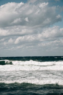 Mavi gökyüzünde beyaz bulutlu deniz sahili manzarası