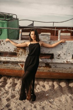 Plajda siyah elbiseli bir kadın kırık bir gemiyle