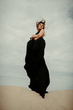 Çölde siyah elbiseli bir kadın 