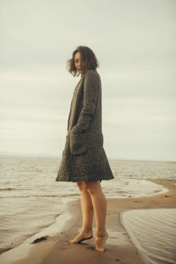 Plajda siyah elbiseli bir kadın kırık bir gemiyle