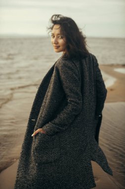 Plajda siyah elbiseli bir kadın kırık bir gemiyle