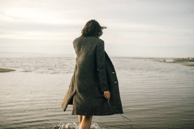 Plajda siyah elbiseli bir kadın kırık bir gemiyle