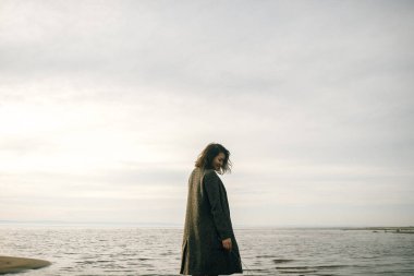 Plajda siyah elbiseli bir kadın kırık bir gemiyle