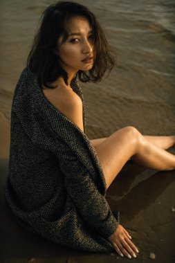 Plajda siyah elbiseli bir kadın kırık bir gemiyle